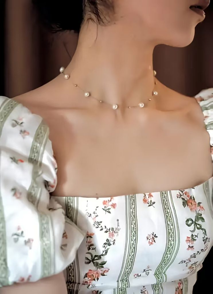 Short necklaces resting just inside the square neckline contribute to an elegant and minimalist winter jewelry aesthetic.